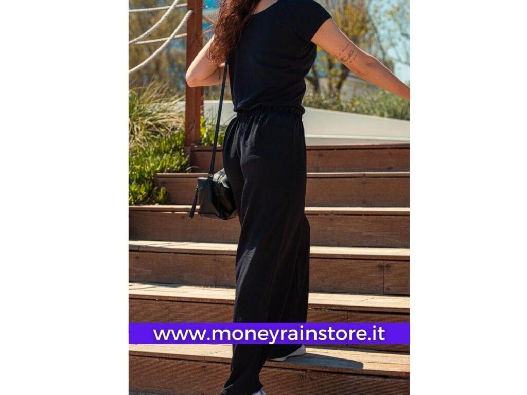 Moda estate 2023 donna: Nella foto una ragazza che sale le scale indossando un pantalone in lino leggero colore nero, completo di maglietta nera e borsa altrettanto nera